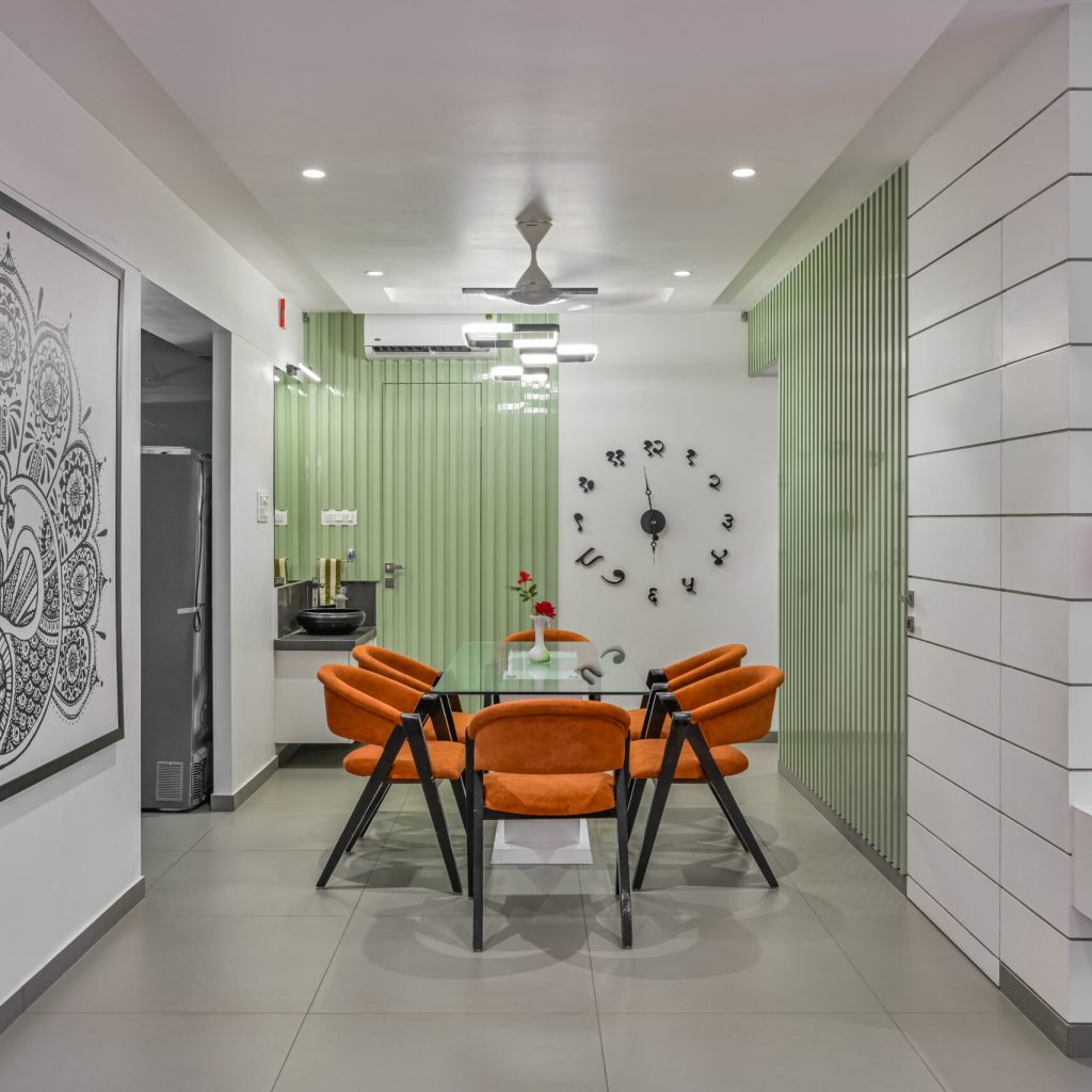 An elegant dining room with a crystal chandelier,a customised wall clock in sanskrit a polished wooden table, and upholstered chairs."